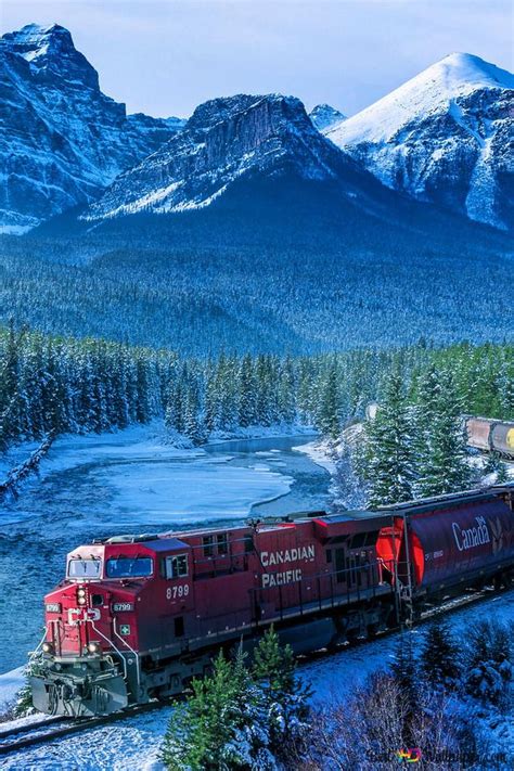 Red train leaving between snowy mountains and forests HD wallpaper download