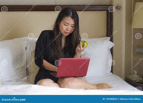 Young Happy And Relaxed Asian Chinese Woman At Hotel Room Bed Working With Laptop Computer