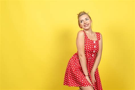 Mujer Joven En Vestido Rojo De Lunares Posando En Amarillo Foto Gratis