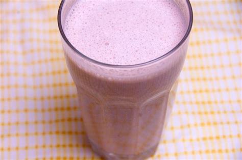 a smoothie is in a tall glass on a yellow and white checkered tablecloth