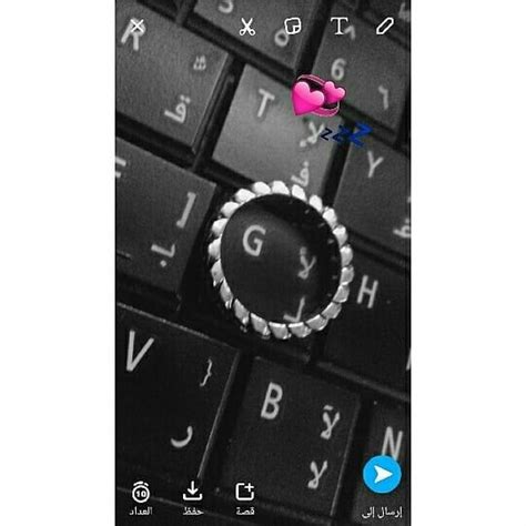 A Ring Sitting On Top Of A Computer Keyboard Next To A Pink And Blue Heart