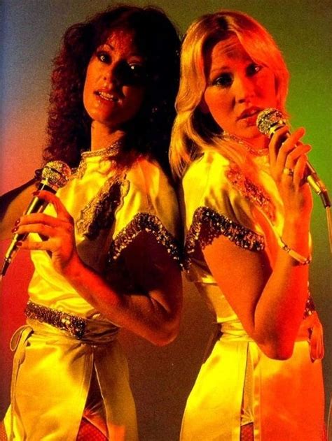 Two Women In Yellow Dresses Are Holding Microphones And Singing Into