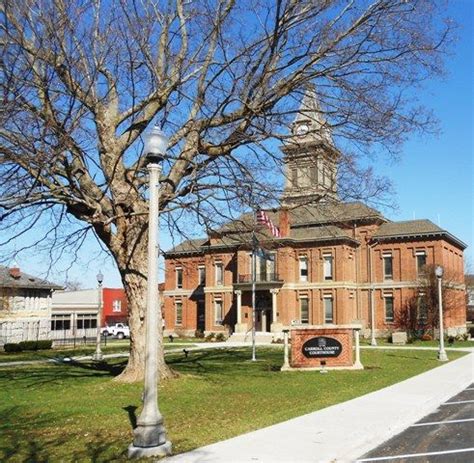 an old brick building with a clock tower on top and a flag pole in front