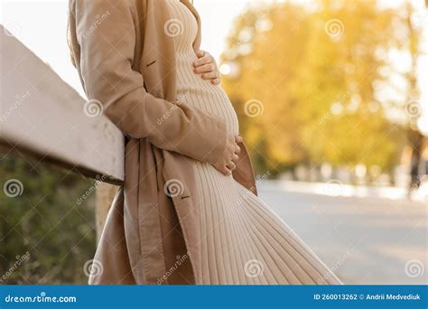 Cropped Photo Of Pregnant Woman Holds Hands On Belly In The Autumn Park