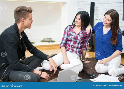 Group Of Three Young Friends Talking While Sitting On Floor At Home