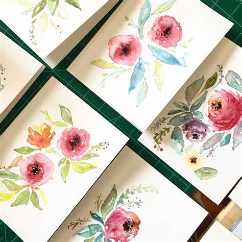 Four Watercolor Paintings With Flowers On Them Sitting On Top Of A