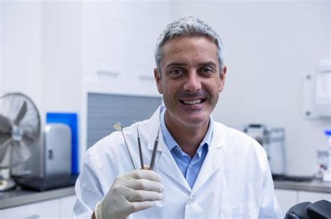 Premium Photo Portrait Of Smiling Dentist Holding Dental Tools