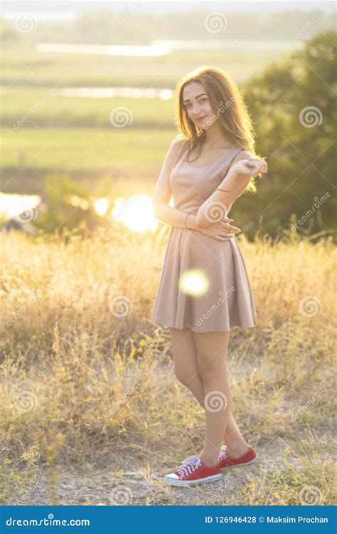 Beautiful Girl Walking In A Field In A Dress At Sunset A Young Woman