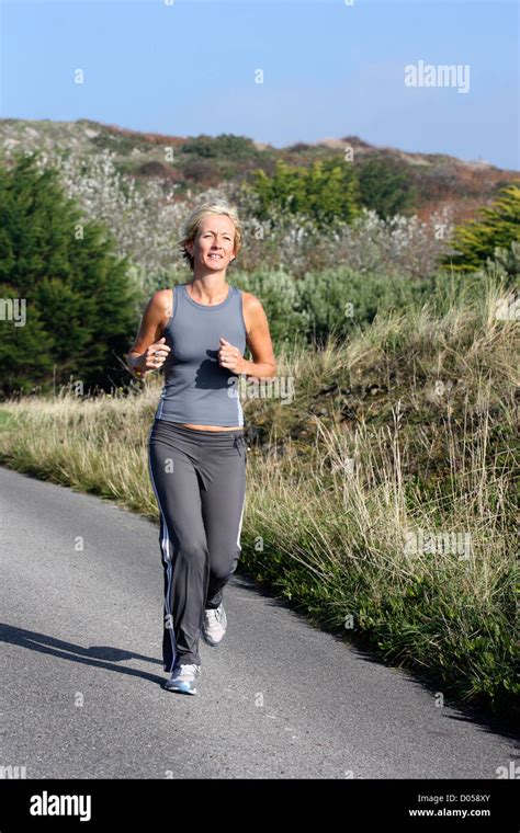 Blonde Woman Outdoors Jogging Along Country Road Stock Photo Alamy