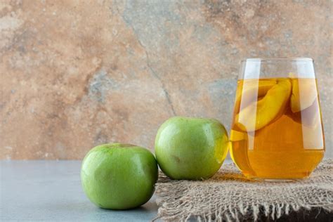 Copo de suco e maçãs frescas na serapilheira Foto Grátis