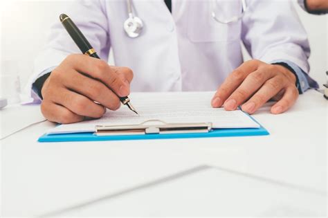 Premium Photo Midsection Of Doctor Writing In Document In Clinic