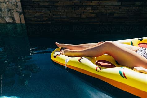 Tan Legs Of Woman Sunbathing On Pizza Floaty In Swimming Pool By