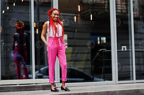 fille afro-américaine à la mode au pantalon rose et aux dreads rouges