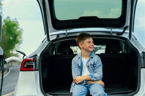 Petit Gar On Assis Sur Le Coffre De La Voiture Tout En Rechargeant Une