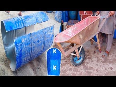 A Man Pushing A Wheelbarrow Next To Blue Barrels