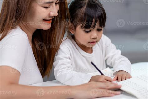 belle femme asiatique aidant sa fille à faire ses devoirs à la maison