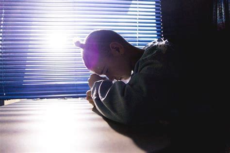 A Man Sitting At A Table In Front Of A Window With The Sun Shining Through