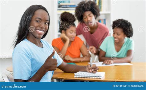 Beautiful Black Female Student At Desk Showing Thumb Up With Group Of