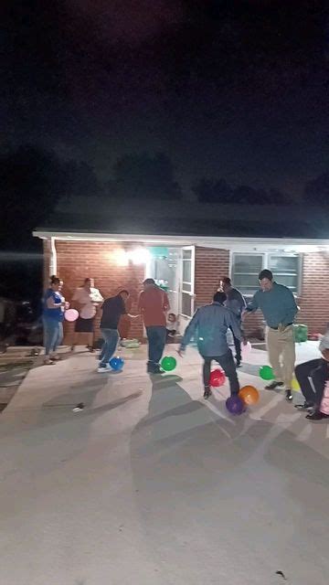 A Group Of People Playing With Frisbees In Front Of A House At Night