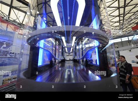 A Visitor Looks At A Model Of A Suspended Monorail System On Display At