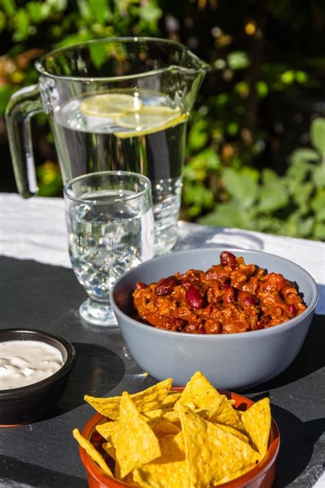 Chilli Con Carne In Ceramic Bowl With Tortilla Chips And Iced Wa Stock