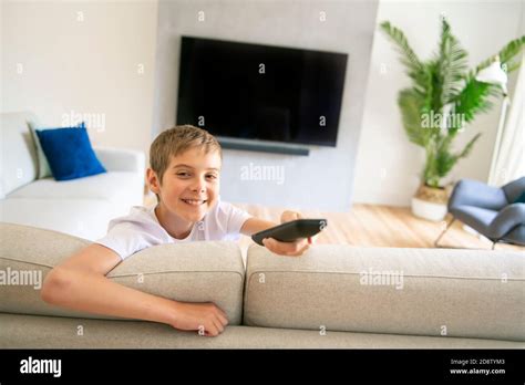 A boy holding remote control and watching TV show Stock Photo - Alamy