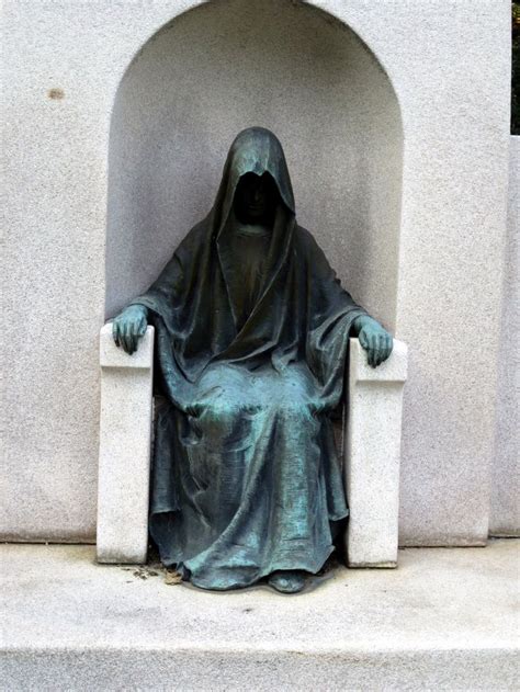 A Statue Of A Nun Sitting On A Bench In Front Of A Cement Wall And Archway