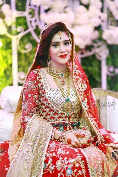 A Woman In A Red And Gold Bridal Outfit Sitting On A White Couch With