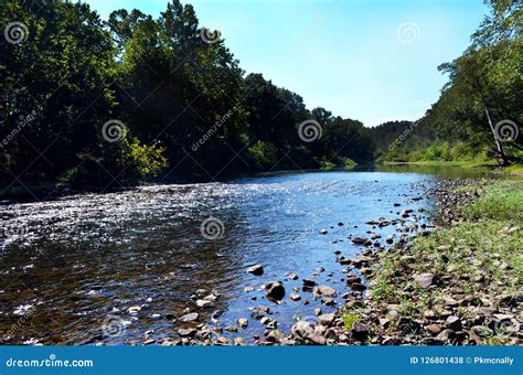 Scenic View Of A Flowing River And Rocky Bank In The Forest Stock Photo