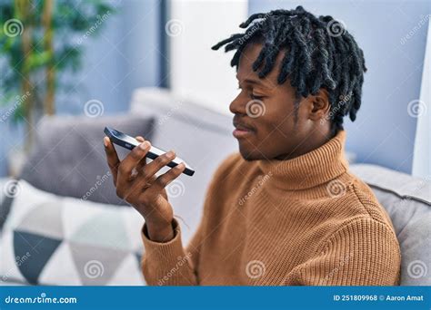 African American Man Talking On The Smartphone Sitting On Sofa At Home