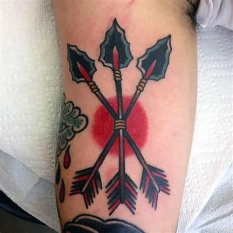 a tattoo on the arm of a person with an open book and two crossed arrows