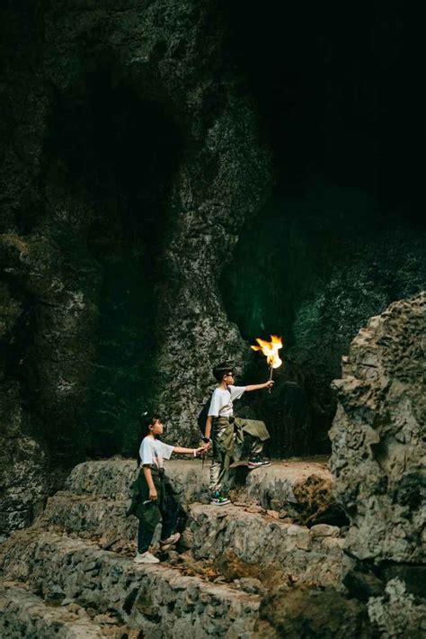 Two Men Standing On Rocks Holding Torches In Their Hands