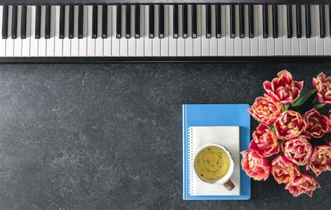 Free Photo Piano Flowers Notepads And A Cup Of Tea On A Dark