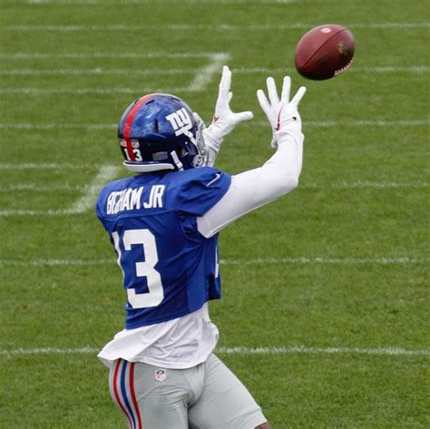 A Football Player Catching A Ball In The Air With His Hands Out To Catch It