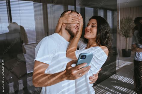 Annoyed Brunette Woman Closing Husbands Eyes By Palms Prohibits Watching Videos Via Internet