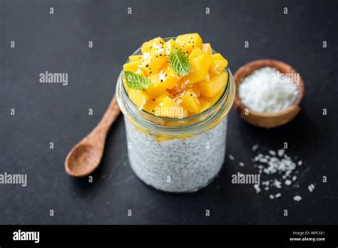 Chia saludable budín con mango y coco en un tarro de vidrio sobre fondo