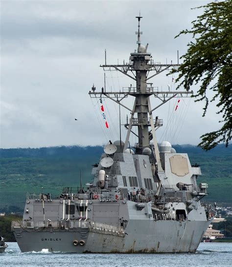 A Large Battleship Floating On Top Of A Body Of Water Next To A Lush