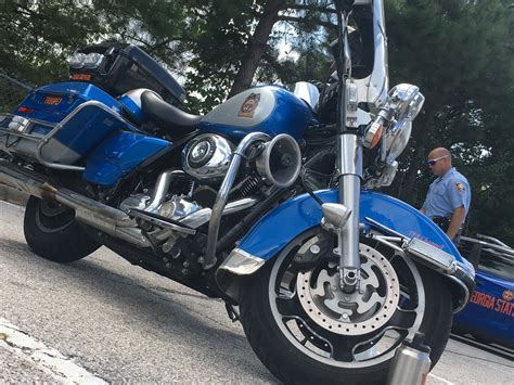 a blue motorcycle parked on the side of the road next to a police ...