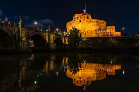 Night view of the Castel Sant'Angelo fortress and the Sant'Angelo bridge reflected in the Tiber ...