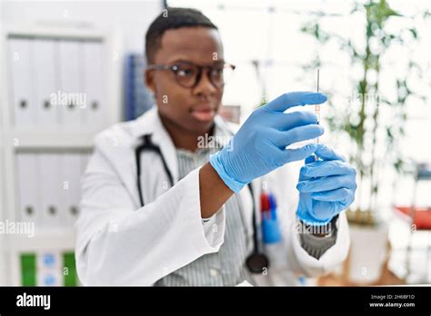 Young African Man Working As Doctor Holding Syringe At Medical Clinic