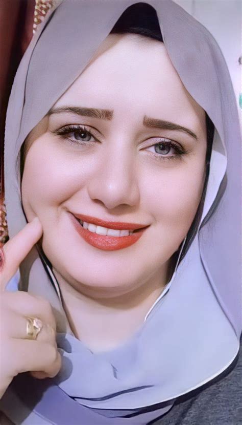 A Woman Wearing A Hijab And Smiling At The Camera With Her Hand On Her Cheek