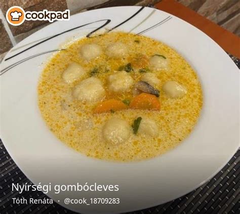 A White Plate Topped With Soup And Dumplings Next To A Glass Of Water