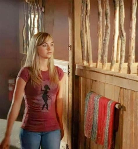 A Woman Standing In Front Of A Bunch Of Sausages Hanging On The Wall