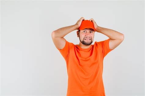 Free Photo Delivery Man Holding Hands On Head In Orange T Shirt Cap