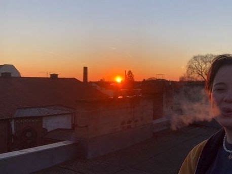 A Woman Standing On Top Of A Roof At Sunset