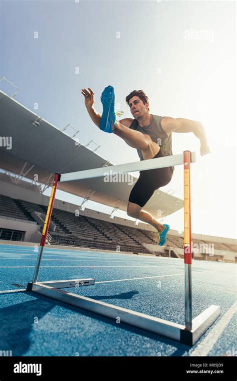 Runner Jumping Over An Hurdle During Track And Field Event Athlete