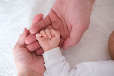 Los padres sostienen la mano de su bebé recién nacido en sus brazos