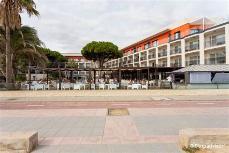 People Are Sitting At Tables In Front Of A Building With Palm Trees On