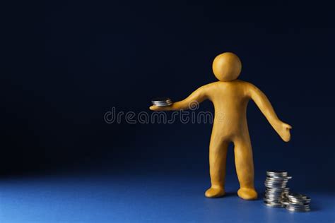 Human Figure Made Of Yellow Plasticine With Coins On Dark Blue