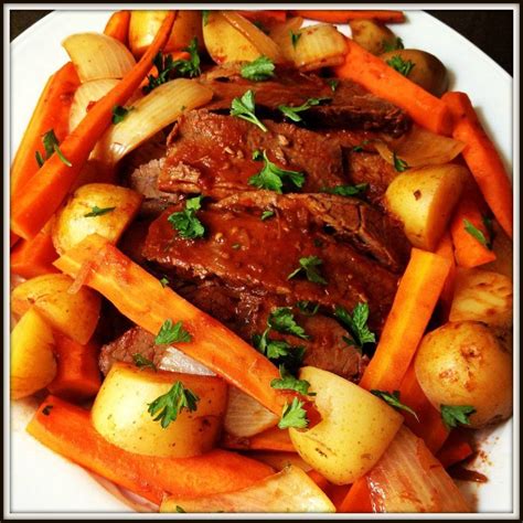 A White Plate Topped With Meat Potatoes And Carrots